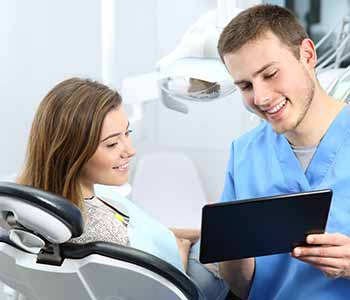 Image of a Dentist showing some reports to patient, Patient is sitting on the dentist chair
